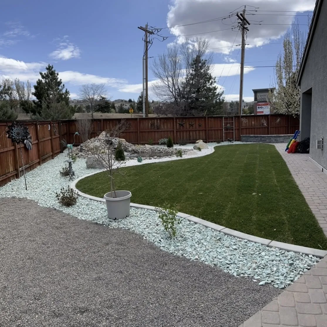 Finished backyard where lawn, pavers, decorative rock, and planting areas meet