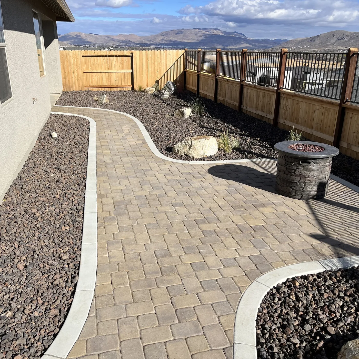 Curved paver walkway and patio with a round fire feature in a finished Reno-area yard