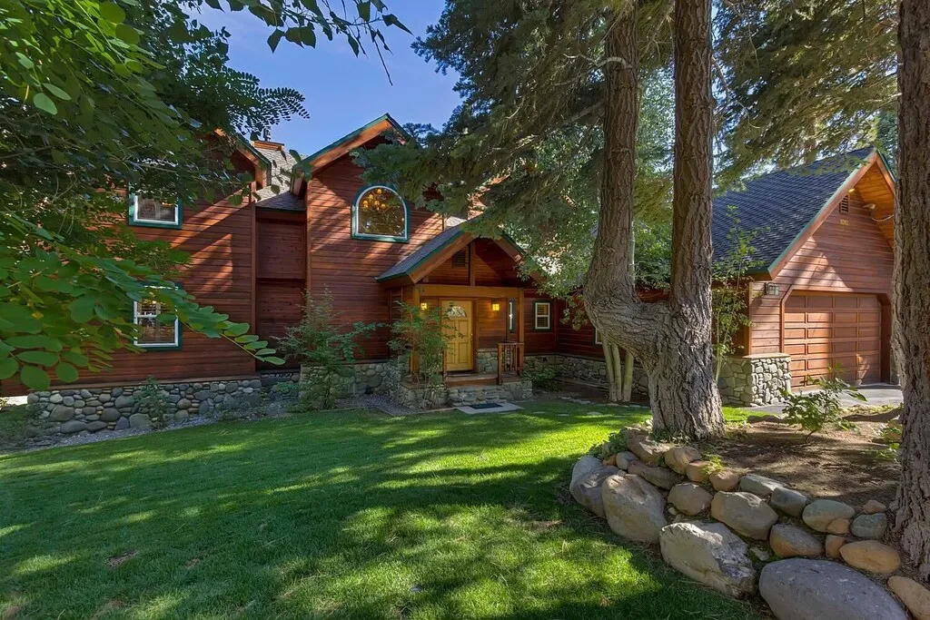 Finished residential yard with lawn, mature trees, and natural stone edging